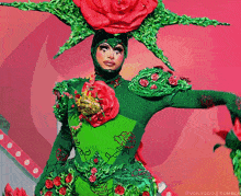 a drag queen is wearing a green and red costume with flowers on it