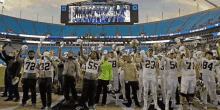 a group of football players are holding up their helmets in a stadium and one of them has the number 55 on his jersey