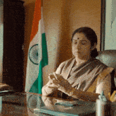 a woman sitting at a desk looking at her cell phone