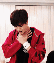 a young man wearing a red jacket with a nike wristband on his wrist