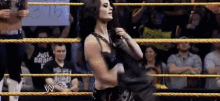 a woman is standing in a wrestling ring with a sign that says ' just bring it ' on it .