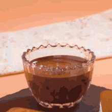 a glass bowl filled with chocolate sauce is on a table