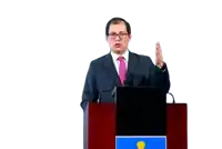 a man in a suit and tie is giving a speech at a podium with a flag on it