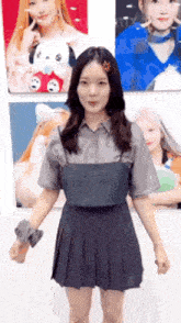 a woman in a pleated skirt is standing in front of a wall with pictures of herself on it .