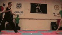 a man and woman are practicing tae kwon do in a gym .