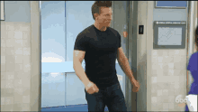 a man in a black shirt stands in front of an elevator that says general hospital emergency exits