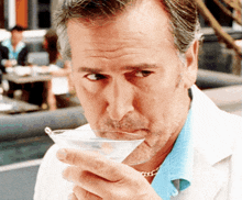 a man drinking from a martini glass with a blue shirt on