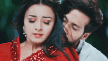 a man is kissing a woman on the forehead while she is wearing a red dress .