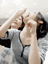 a woman in a striped shirt is drinking water
