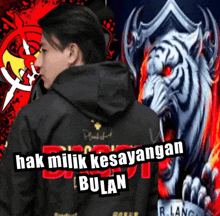 a man wearing a black hoodie with hak milik kesayangan bulan on the back