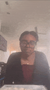 a woman wearing glasses sits at a table