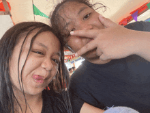 two young girls are making funny faces and one is pointing at her nose