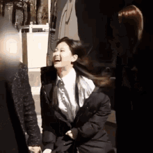 a woman in a black coat is laughing while sitting on a bench