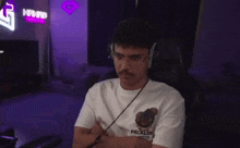 a man wearing headphones is sitting in a chair with his arms crossed and looking at the camera .