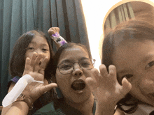 a woman wearing glasses is surrounded by two young girls making funny faces