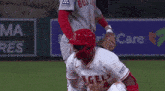 a baseball player with the word angels on his shirt is kneeling down on the field .
