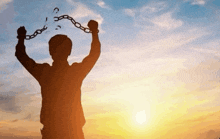 a silhouette of a man holding chains up in the air