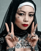a woman with a tattoo on her face is wearing a nun costume and giving a peace sign