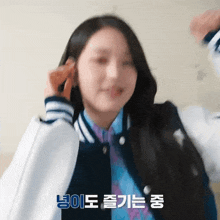 a woman wearing a baseball jacket and a blue shirt has korean writing on the bottom