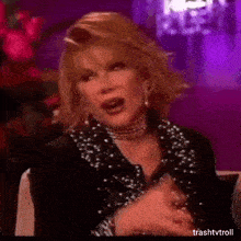 a woman wearing a choker and a black jacket is sitting on a couch .
