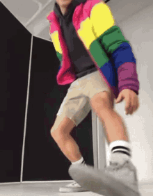 a person wearing a rainbow jacket and khaki shorts is dancing