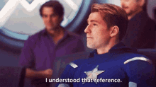 a man in a captain america uniform is sitting in front of a group of people and saying `` i understood that reference . ``