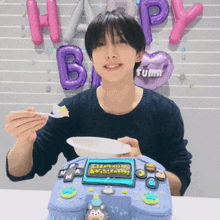 a young man is eating a cake with balloons behind him that say happy birthday