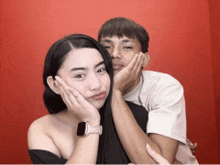 a man and a woman are posing for a picture against a red background