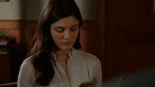 a woman is sitting in a chair looking at her phone .