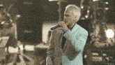 a man in a suit sings into a microphone in front of a marshall speaker