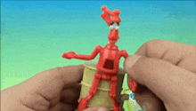 a person is holding a red toy robot on a barrel