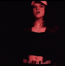 a woman wearing a hat and a checkered belt is singing