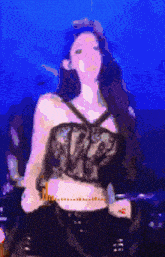 a woman in a crop top is dancing on a stage in front of a blue background