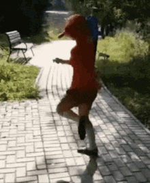 a person in a red shirt is walking down a brick path