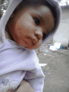 a baby wearing a purple hoodie is being held by someone