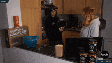 a man and a woman are standing in a kitchen with a box that says nichts als adventsliebe