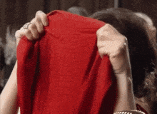 a woman covering her face with a red cloth