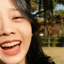 a close up of a woman 's face with her mouth open and a tree in the background .