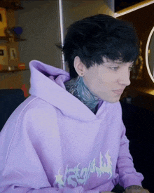 a man wearing a purple hoodie with a dragon on the front