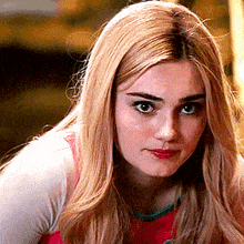 a woman with blonde hair is wearing a pink shirt