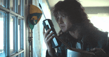 a man with long hair is talking on a cell phone in front of a door