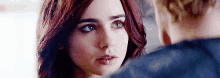 a man and a woman are looking at each other . the woman has red hair and the man has blue hair .