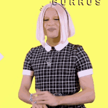 a woman with pink hair is wearing a black and white plaid dress and a necklace .