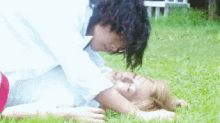 a man and a woman are laying on the grass and kissing .