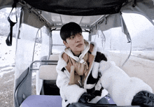 a young man in a fur coat is sitting in a golf cart
