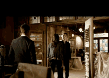 a man in a suit and a woman in a black jacket are standing in a dark room