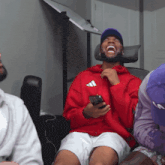 a man wearing a red adidas hoodie is laughing