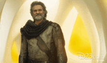 a man with a beard is standing in front of a yellow and white circle with disney.com written on the bottom