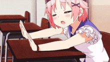 a girl with pink hair is sitting at a desk making a stop sign