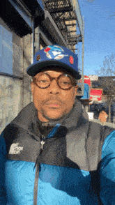 a man wearing a blue jays hat and a north face jacket takes a selfie